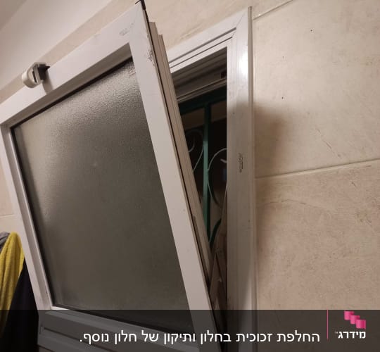 חלון פתוח עם תריסים לבנים על קיר בהיר